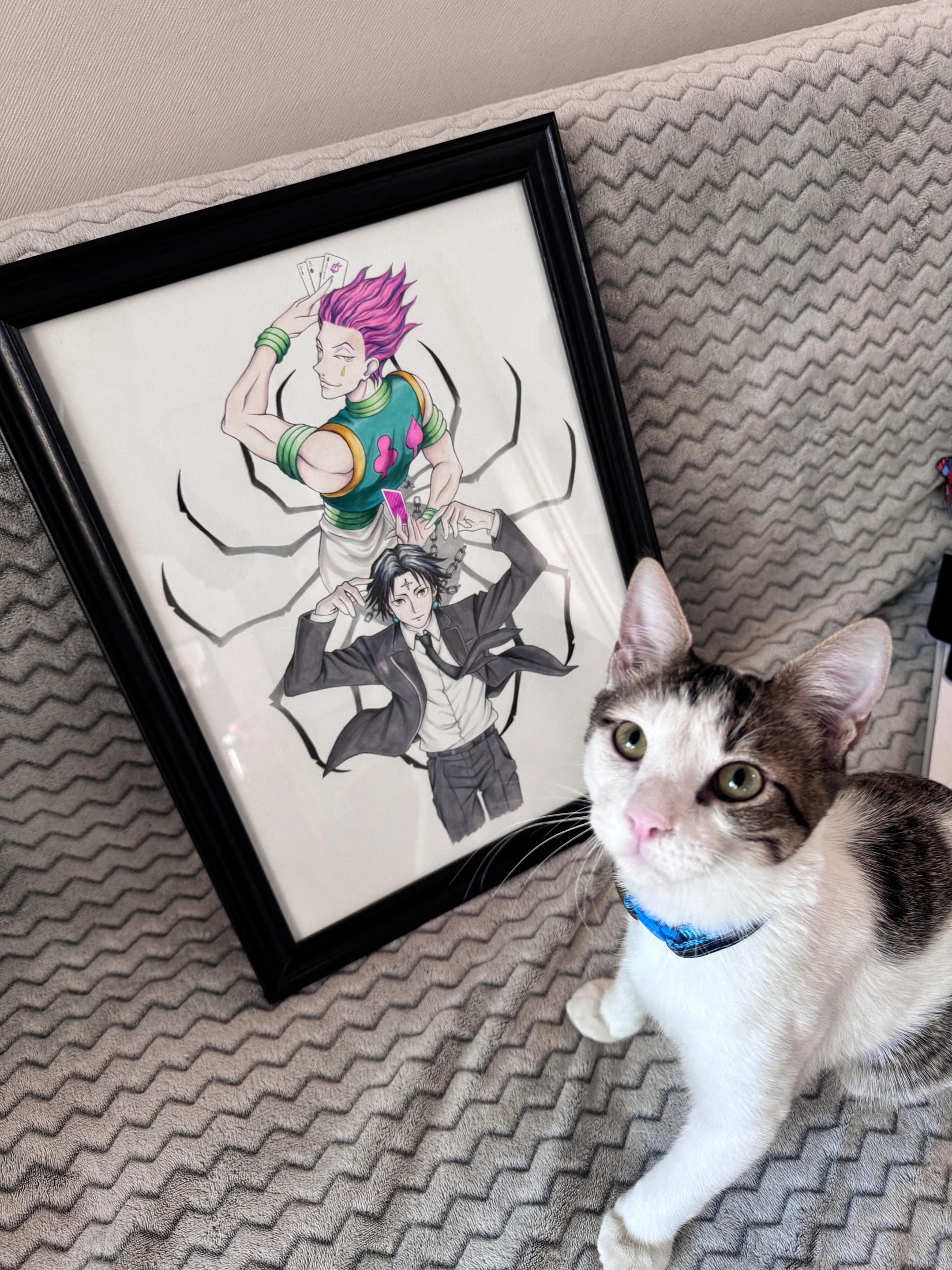 Ilustración enmarcada de Hisoka y Chrollo de Hunter x Hunter junto a un gato