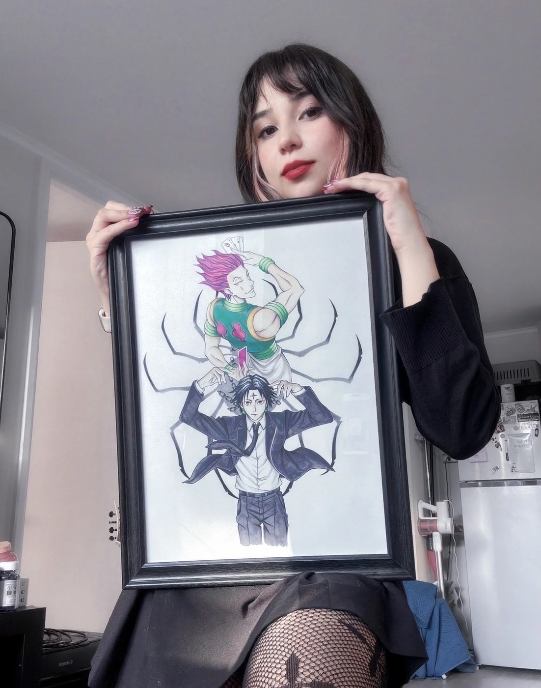 Javiera sosteniendo una de sus ilustraciones enmarcadas de personajes de anime
