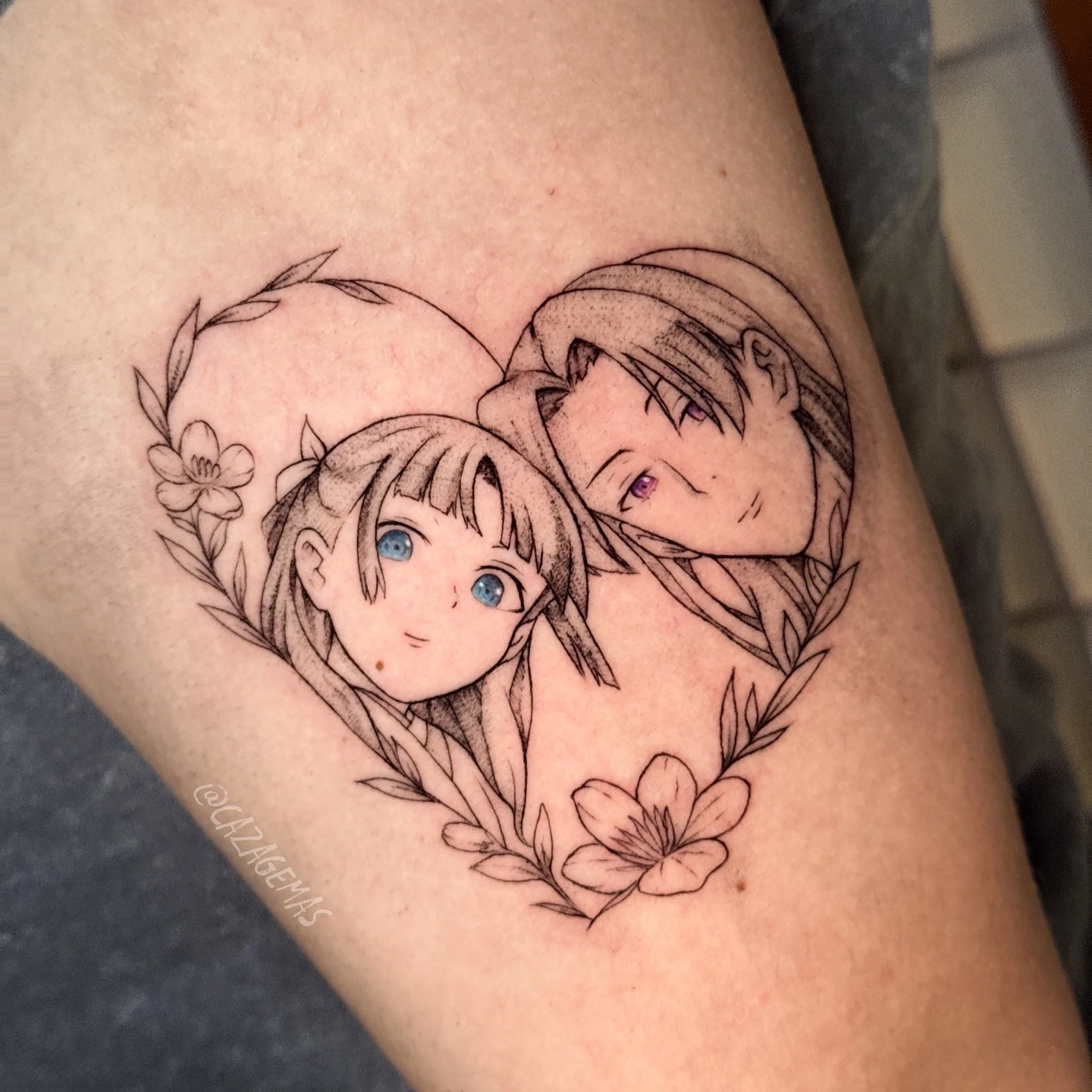 Tatuaje de dos personajes de anime abrazados dentro de un corazón de flores